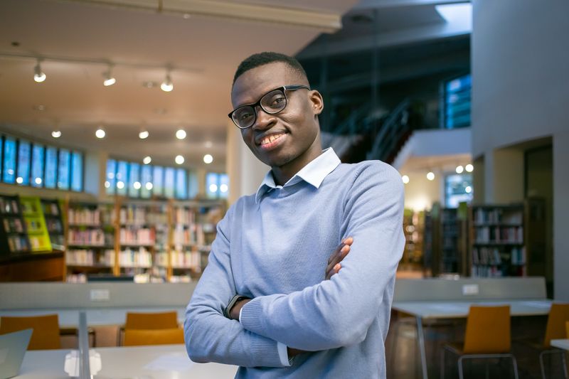 A confident university student standing in a library